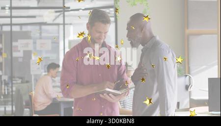 Puntare l'uomo con una camicia rossa che rivede il notebook con un collega che ascolta i monitor in un ufficio moderno Foto Stock