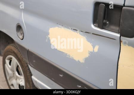 Portiera del veicolo danneggiata con rimozione parziale della vernice in un garage Foto Stock