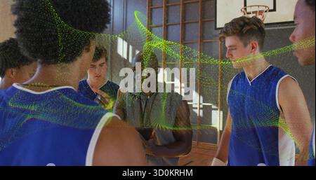 Raduna i giocatori allenati in maglie blu sul campo all'interno della palestra con tablet, canestro e barre a muro Foto Stock