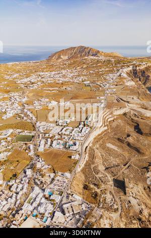 Foto con droni che cattura l'ampio paesaggio vulcanico e i villaggi bianchi sparsi di Santorini Foto Stock