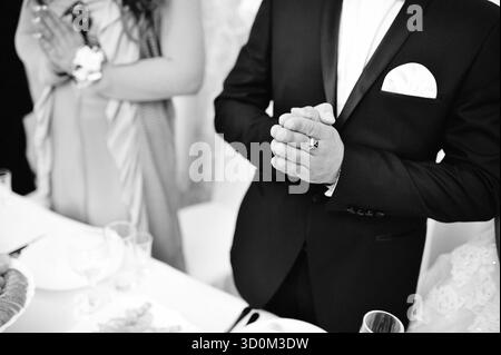 Coppia di nozze al tavolo del ristorante, mani piegate per la preghiera Foto Stock