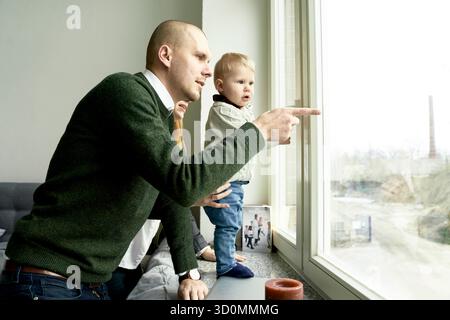 padre che mostra al bambino il mondo fuori dalla finestra Foto Stock