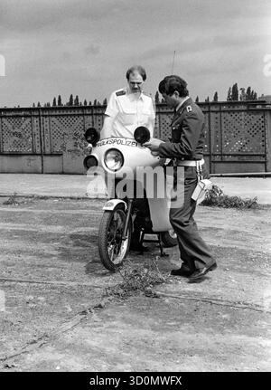 DEU, Germania, Berlino, 1990-03-18: I poliziotti di Berlino Ovest e Est si incontrano sul ponte Behmstrasse al confine tra il distretto occidentale di Wedding e il distretto orientale di Prenzlauer Berg. Una pattuglia motociclistica Volkspolizei mostra a un poliziotto di Berlino Ovest la sua moto. HF [traduzione automatizzata] Foto Stock