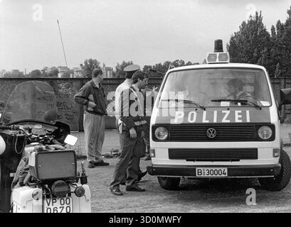 DEU, Germania, Berlino, 1990-03-18: Gli agenti di polizia di Berlino Ovest e Est si incontrano sul ponte Behmstrassenbruecke al confine tra il quartiere occidentale di Wedding e il quartiere orientale di Prenzlauer Berg. A sinistra nella foto c'è una pattuglia motociclistica della polizia popolare, a destra un autobus della polizia di Berlino Ovest, sullo sfondo un membro delle truppe di frontiera della RDT e un poliziotto in abiti civili. [traduzione automatizzata] Foto Stock