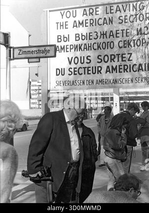 DEU, Germania, Berlino, 1990-03-18: L'ambasciatore DEGLI STATI UNITI Vernon Walters visita l'ex Checkpoint Charlie su Friedrichstrasse con la moglie (a sinistra) e la figlia (in alto a destra) durante una visita privata a Berlino. Walters di fronte al cartello di settore all'angolo con Zimmerstrasse. Sullo sfondo è presente il checkpoint abbandonato sul lato GDR. HF [traduzione automatizzata] Foto Stock