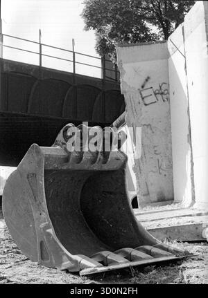 DEU, Germania, Berlino, 1990-03-18: Una pala da escavatore e segmenti di cemento strappati dal loro ancoraggio annunciano la caduta finale del muro di Berlino. Vista su Kiefholzstrasse al confine tra i distretti di Neukoelln (ovest) e Treptow (est). Sullo sfondo il ponte della Ringbahn ancora interrotta. HF [traduzione automatizzata] Foto Stock