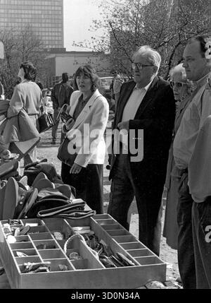 DEU, Germania, Berlino, 1990-03-18: Con la moglie (a destra) e la figlia (a sinistra), l'ambasciatore americano Vernon Walters visita il negozio di souvenir della DDR presso l'ex Checkpoint Charlie su Friedrichstrasse durante una visita privata a Berlino. Walters allo stand con berretti uniformi e insegne di rango. Il grattacielo Springer sullo sfondo. HF [traduzione automatizzata] Foto Stock