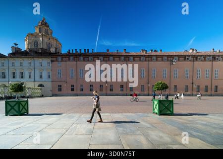 Persone che camminano e pedalano attraverso Piazza Castello con la storica cupola della Sacra Sindone visibile sullo sfondo. Torino, Italia. 10.06.2 Foto Stock