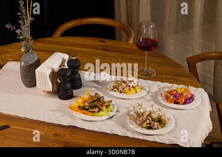 Un elegante ambiente da pranzo con una serie di piatti assortiti accompagnati da ottimo vino rosso Foto Stock
