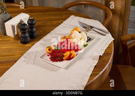 Un vivace e colorato vassoio di frutta fresca su uno splendido tavolo in legno che trasuda fascino Foto Stock