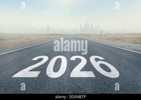 iscrizione 2026 scritta su strada autostradale in mezzo a strada asfaltata vuota e bel cielo blu. Concetto per VISION nuovo anno 2026. visione futura. Foto Stock