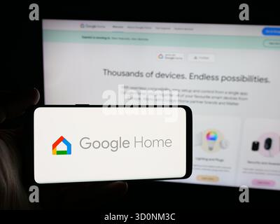 Stoccarda, Germania - 18-10-2025: Persona che possiede uno smartphone con il logo della società statunitense di smart home Google Home sullo schermo di fronte al sito Web. Foto Stock