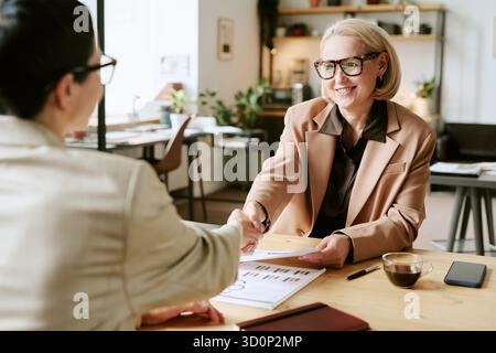 Donna anziana che stringe la mano a una giovane donna adulta durante l'incontro Foto Stock