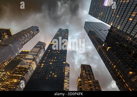 Una spettacolare vista verso l'alto dei torreggianti grattacieli di vetro di Hudson Yards a Midtown Manhattan, New York, di notte sotto un cielo nuvoloso. Foto Stock