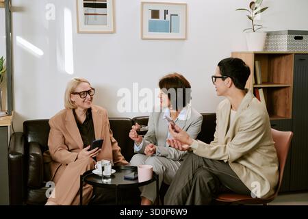 Tre donne di mezza età che conversano durante la pausa caffè Foto Stock