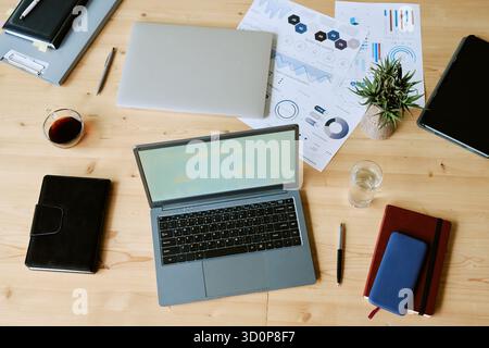 Vista dall'alto di laptop e documenti aziendali che si occupano della disposizione su Office Desk Foto Stock
