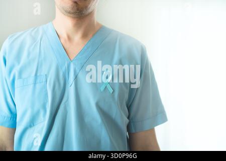 Primo piano di un giovane professionista sanitario in uniforme con nastro di raso blu. Simbolo della consapevolezza del cancro alla prostata, della prevenzione e della diagnosi medica precoce. Foto Stock