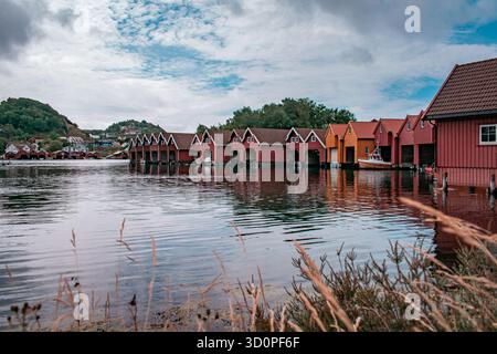 Una fila di barche colorate con barche attraccate all'interno, che si riflettono sull'acqua calma. Foto Stock