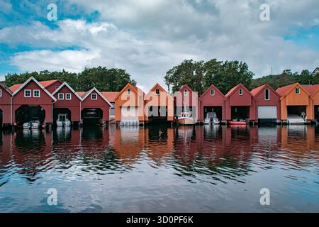 Una fila di barche colorate con barche attraccate all'interno, che si riflettono sull'acqua calma. Foto Stock