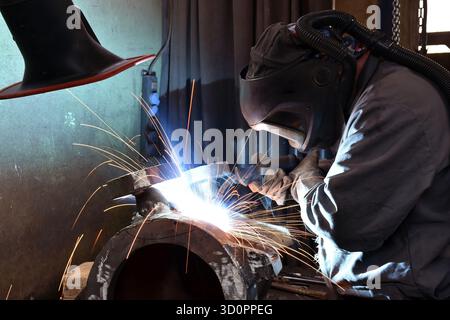 Saldatore di indumenti protettivi sul posto di lavoro in un'azienda industriale di costruzioni in acciaio - foto ravvicinata Foto Stock