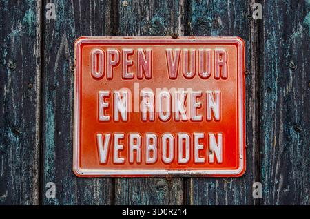 Un cartello rosso, che indica in olandese che fumare e aprire il fuoco è vietato, su un muro di legno intemprato Foto Stock