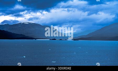 La tranquilla scena cattura la bellezza della natura con un lago tranquillo e una catena montuosa lontana Foto Stock