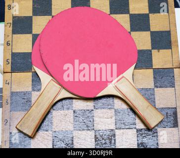 Due pale rosse da ping pong sono piatte su una tavola a scacchi con marcatori di gioco, pronte per essere giocate in una partita amichevole. Foto Stock