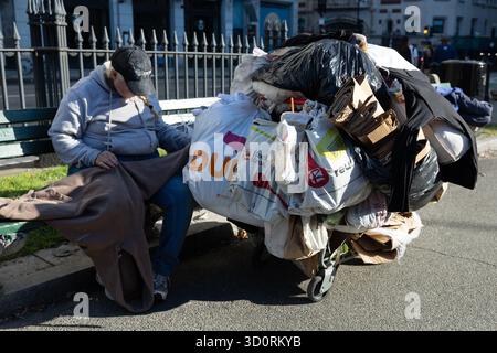 Senzatetto seduto sulla panchina con effetti personali a Boston Common Foto Stock