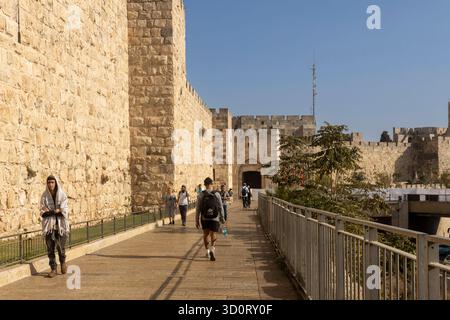 Gerusalemme, Israele, 23 ottobre 2025, la gente cammina lungo la passeggiata sopraelevata accanto alle massicce e storiche mura di pietra della città vecchia. Vicino a Jaffa Gat Foto Stock