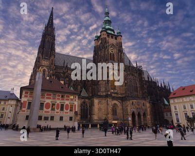 Cattedrale gotica di San Vito al Castello di Praga al crepuscolo con un cielo nuvoloso e i turisti Foto Stock