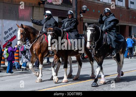 Toronto, ONTARIO, Canada - 24 ottobre 2025: Tre agenti di polizia a cavallo in uniformi nere cavalcano i loro cavalli lungo una strada durante una parata. Foto Stock