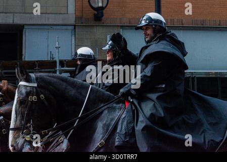 Toronto, ONTARIO, Canada - 24 ottobre 2025: Tre agenti di polizia a cavallo in uniformi nere cavalcano i loro cavalli lungo una strada durante una parata. Foto Stock