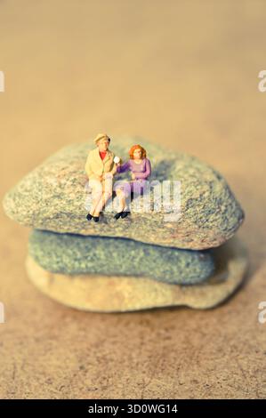 Statuette in miniatura di coppie anziane sedute su pietre impilate, foto concettuale di amore e compagnia Foto Stock