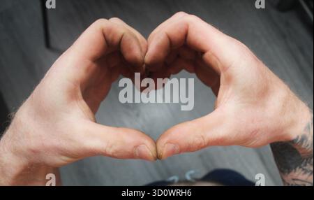 Un uomo mostra il suo cuore con le mani. Simbolo cuore. Foto Stock