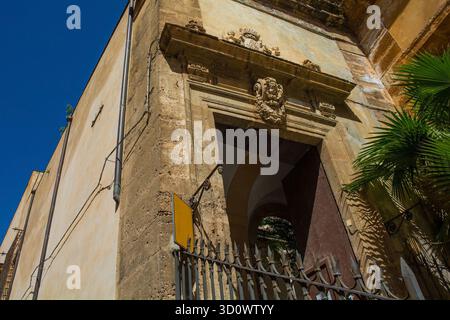 L'ingresso laterale di una vecchia chiesa a Palermo, Sicilia, Italia. Barocco, XVII o XVIII secolo. La porta è incorniciata da un portale in pietra con un cherubino intagliato Foto Stock