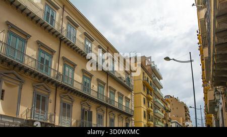 Una strada nel quartiere Politeama di Palermo in Sicilia, Italia. A sinistra, un elegante edificio neoclassico del tardo XIX secolo con facciata simmetrica. Foto Stock