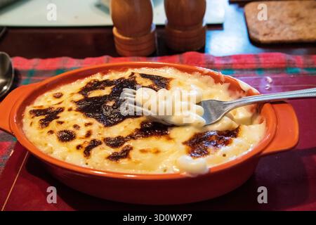 Cremosi macaroni in un piatto di ceramica arancia, condimento al forno dorato, forchetta con la pasta, concetto di cibo confortevole. Foto Stock
