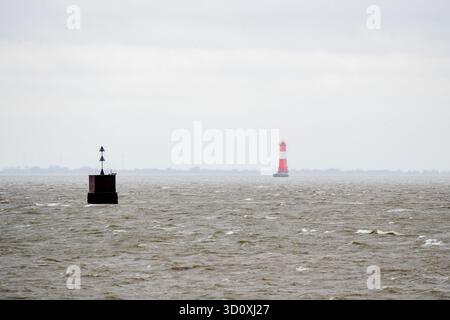 Wilhelmshaven, Germania. 25 ottobre 2025. Un segno di mare e il faro di Arngast sorgono nella Baia di Giada in condizioni di pioggia. Dopo la depressione della tempesta 'Joshua', il tempo nella bassa Sassonia è rimasto tempestoso e piovoso durante il fine settimana. Crediti: Hauke-Christian Dittrich/dpa/Alamy Live News Foto Stock