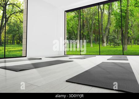 Spazioso studio yoga con tappetini per esercizi e grandi finestre. Design degli interni Foto Stock