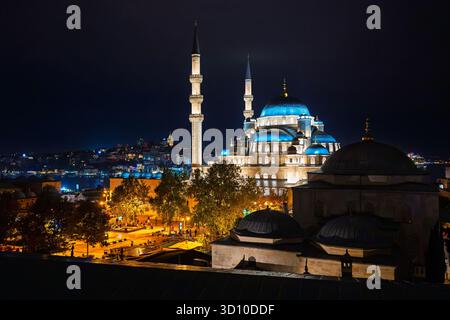 La Moschea Yeni illuminata, conosciuta anche come la nuova Moschea, con la Torre di Galata e lo stretto del Bosforo in vista dietro, a Istanbul, Turchia. Foto Stock