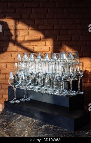 Eleganti oggetti in vetro disposti in file sotto la luce dorata, perfetti per eventi di lusso, marchi da bar o immagini minimaliste per l'ospitalità. Foto Stock