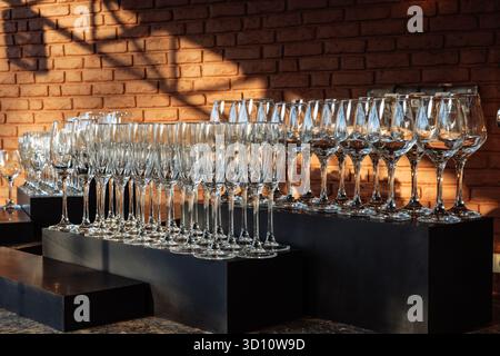 Eleganti oggetti in vetro disposti in file sotto la luce dorata, perfetti per eventi di lusso, marchi da bar o immagini minimaliste per l'ospitalità. Foto Stock
