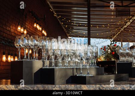 Eleganti oggetti in vetro disposti in file sotto la luce dorata, perfetti per eventi di lusso, marchi da bar o immagini minimaliste per l'ospitalità. Foto Stock