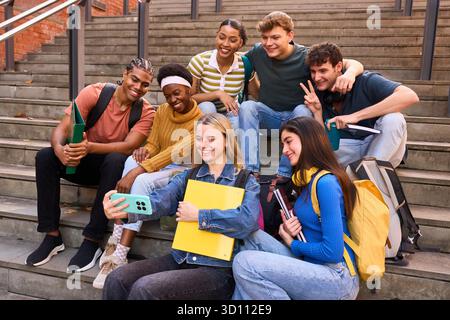 Gruppo di studenti universitari diversi che si fanno un selfie gioioso Foto Stock