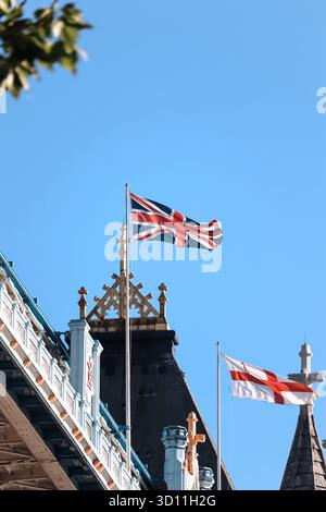 Londra, Inghilterra - 11 agosto 2022: Primo piano delle bandiere Union Jack e St George's Cross che sorvolano la struttura del Tower Bridge in estate Foto Stock