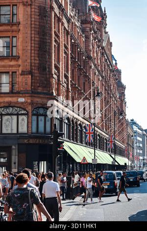 Londra, Inghilterra - 13 agosto 2022: L'esterno del famoso grande magazzino Harrods con la storica facciata in terracotta e l'entrata affollata di Knightsbridge Foto Stock