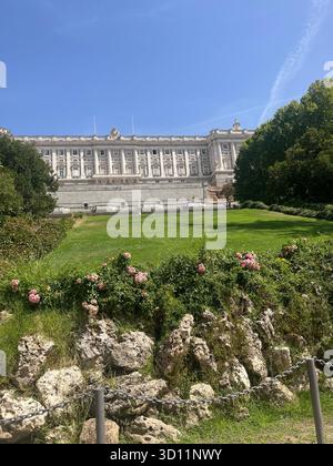 Vista estetica del Palazzo reale di Madrid da campo del Moro con fiori, alberi, vegetazione e un cielo azzurro limpido in un giorno d'estate soleggiato. Foto Stock