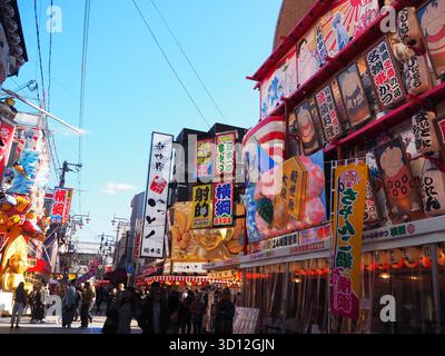 Via Shinsekai con cartelli colorati per ristoranti e vivaci negozi vicino a Tsutenkaku, nel quartiere dei divertimenti retrò di Osaka Foto Stock