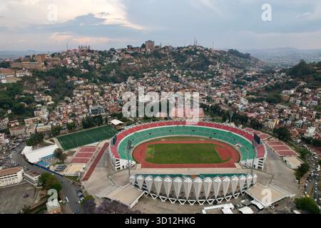 Antananarivo, Madagascar – 24/10/2023: Alto panorama obliquo dello Stadio Mahamasina, quartiere centrale degli affari, colline residenziali, fioritura di jacaranda. Foto Stock