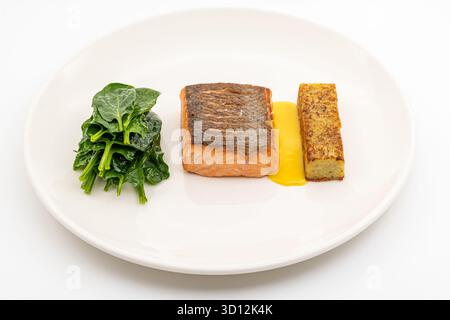 Filetto di salmone scottato servito con spinaci saltati e croquette di patate Foto Stock